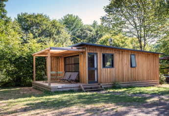 Houten lodge bij Chalet Toronto met overdekte veranda, tuinstoelen en groene bomen op de achtergrond.