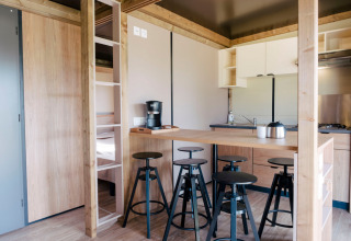 Moderne indretning af Chalet Toronto i Huttopia De Roos, Nederlandene, med køkken og barstole.