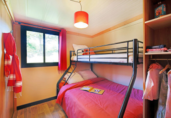Sfeervolle slaapkamer in Chalet Toronto bij Huttopia De Roos, Nederland, met stapelbed en open kast.