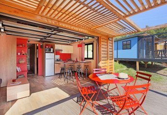 Lyst, moderne chalet med åbent køkken og farverige møbler på terrassen i Huttopia De Roos, Holland.