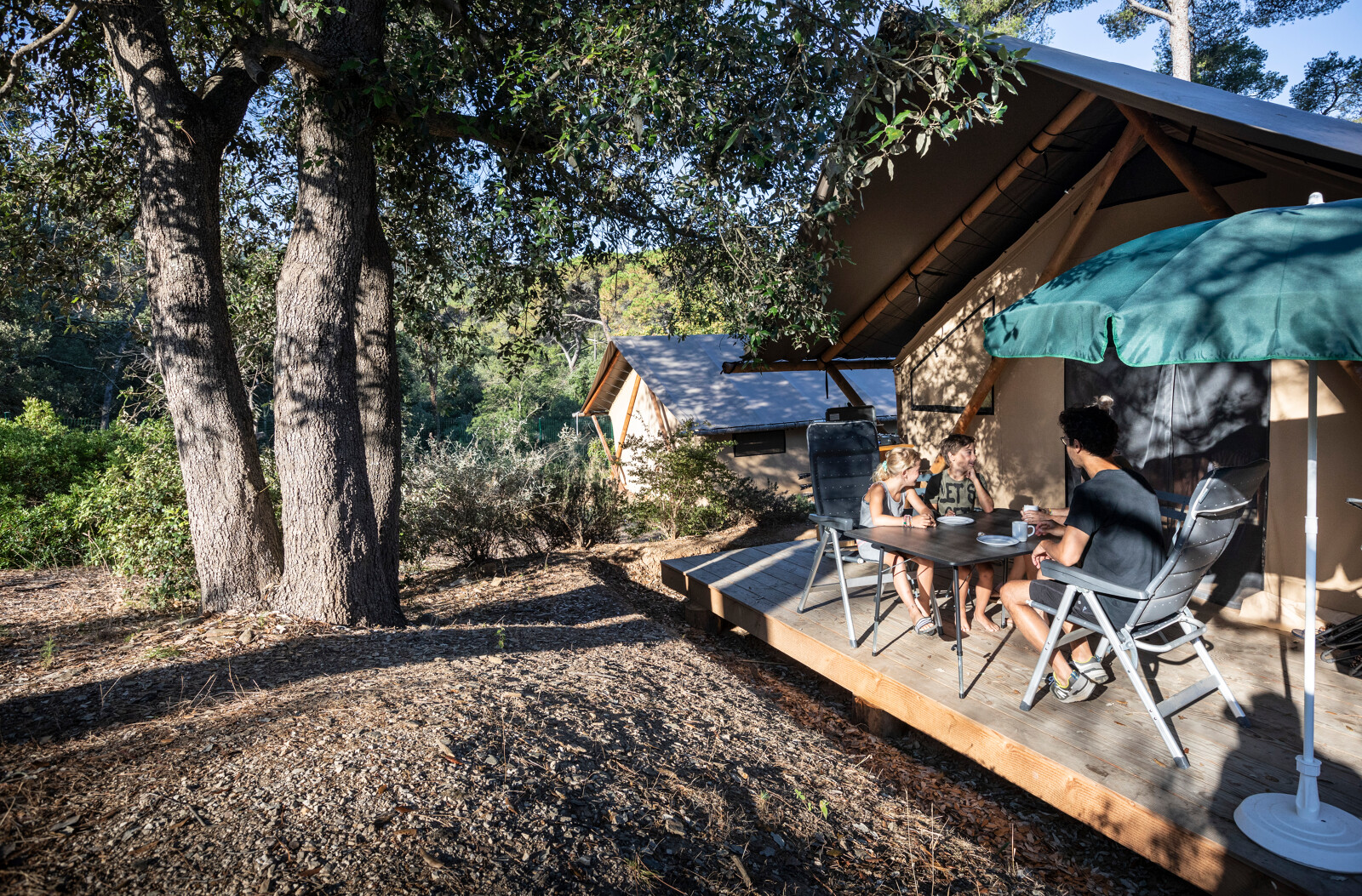 Gezin ontspant buiten bij een Trappeur safari tent op Huttopia Lac de l'Uby - Gers in Frankrijk, in de natuur.