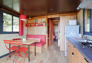 Interior luminoso y acogedor de una caravana gitana en Huttopia Parque de Doñana con comedor y cocina pequeña.