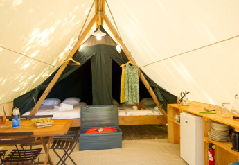 Indvendig af en Canadienne safari telt på Huttopia Parque de Doñana i Spanien, med senge, bord og køkkenudstyr.