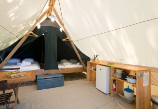 Indersiden af et Canadienne safari telt med senge, køkkenfaciliteter og spisebord på Huttopia Parque de Doñana.