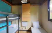 Moderne glamping accommodatie bij Chalet Evasion met stapelbed, enkel bed, kast en raam.