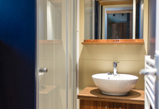 Moderne badkamer bij Chalet Evasion glamping met houten kast, ronde wastafel en glazen douchecabine.