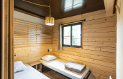 Gezellige slaapkamer in Chalet Portland met twee enkele bedden, houten wanden en een raam.