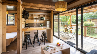 Moderno glamping Chalet Portland con interior de madera clara, cocina abierta y amplia terraza amueblada.