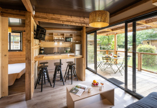 Moderno glamping Chalet Portland con interior de madera clara, cocina abierta y amplia terraza amueblada.