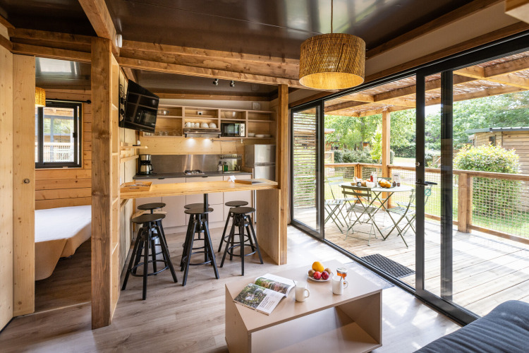Modernes Glamping Chalet Portland mit hellem Holzinterieur, offener Küche und möblierter Terrasse.