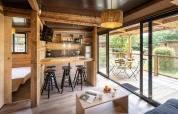 Moderno glamping Chalet Portland con interior de madera clara, cocina abierta y amplia terraza amueblada.