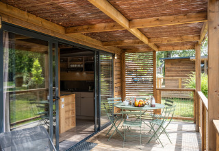 Houten veranda van Chalet Portland met ontbijttafel en stoelen, uitkijkend op groene tuin.