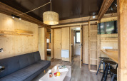Alojamiento glamping Chalet Portland con interior de madera, sofá, mesa de bar, TV y detalles modernos.