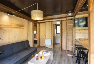 Contemporary glamping suite at Chalet Portland featuring wood interior, sofa, bar, TV and cozy decor.