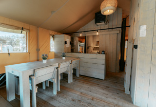 Interior de una cabaña de madera acogedora con mesa de comedor y cocina en Camping de Italiaanse Meren.
