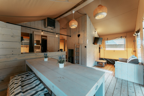 Lyst, rustikt interiør i en hytte på Camping de Italiaanse Meren i Holland med spisebord og sofa.