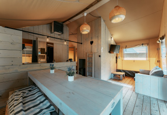 Lyst, rustikt interiør i en hytte på Camping de Italiaanse Meren i Holland med spisebord og sofa.