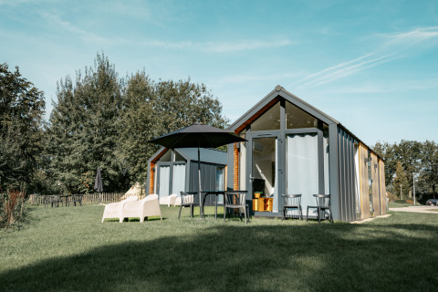 Tiny house Oslo Suite au Camping de Italiaanse Meren aux Pays-Bas, entourée de verdure et de mobilier d’extérieur.
