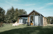 Moderne Oslo Suite tiny house ved Camping de Italiaanse Meren i Holland, omgivet af grønne træer og græs.