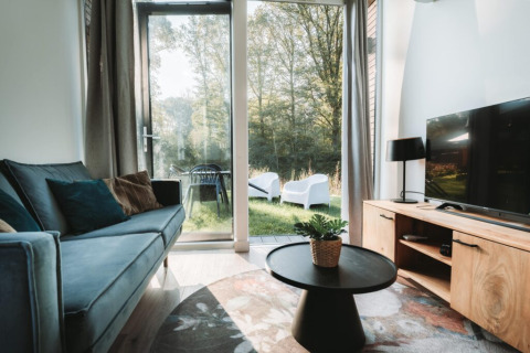 Modernes Wohnzimmer der Oslo Suite mit Gartenblick im Camping de Italiaanse Meren in den Niederlanden.
