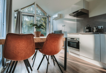 Moderne spiseplads med lænestole og åbent køkken i Oslo Suite på Camping de Italiaanse Meren, Holland.