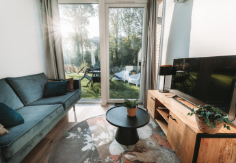 Stue i Oslo Suite tiny house ved Camping de Italiaanse Meren i Holland, med udsigt til have gennem glasdør.