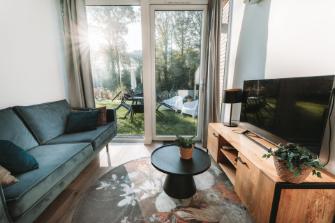 Wohnbereich im Oslo Suite Tiny House bei Camping de Italiaanse Meren in den Niederlanden mit Gartenblick.