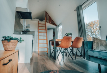 Moderne Oslo Suite tiny house ved Camping de Italiaanse Meren i Holland med hems, spisebord og store vinduer.