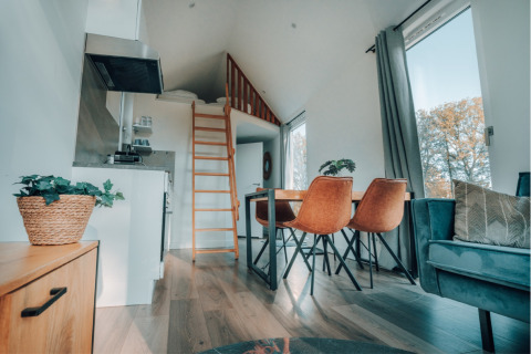 Moderne tiny house Oslo Suite op Camping de Italiaanse Meren in Nederland met slaapzolder en eethoek.