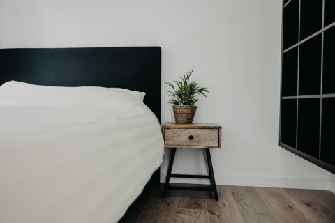 Soveværelse i Oslo Suite ved Camping de Italiaanse Meren med sort sengegavl og natbord med plante.