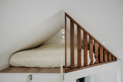 Cama en altillo con barandilla de madera en Oslo Suite, Camping de Italiaanse Meren, Países Bajos.