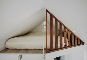 Gemütliches Dachbett mit Holzgeländer in der Oslo Suite im Camping de Italiaanse Meren, Niederlande.