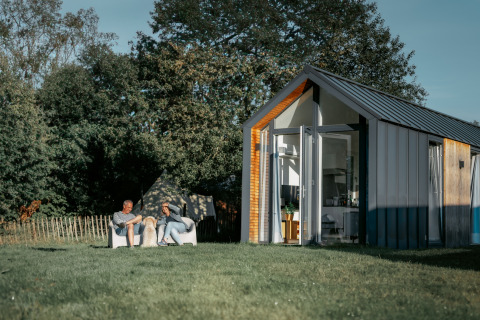 Dos personas relajándose fuera de la tiny house Oslo Suite en Camping de Italiaanse Meren, Países Bajos.