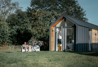 Dos personas relajándose fuera de la tiny house Oslo Suite en Camping de Italiaanse Meren, Países Bajos.