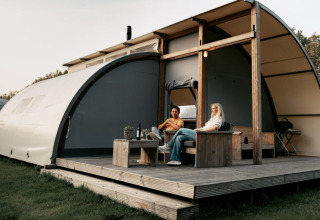 Twee mensen relaxen op de veranda van een Arcade-lodge bij Camping de Italiaanse Meren in Nederland.