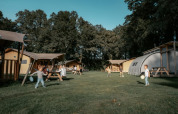 Børn leger på en grøn græsplæne foran Arcade Lodge på Camping de Italiaanse Meren i Holland.