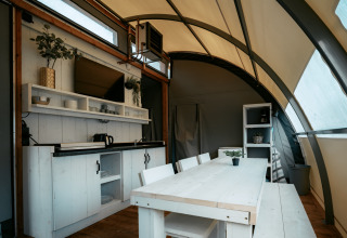 Interno della Arcade lodge al Camping de Italiaanse Meren nei Paesi Bassi, con cucina e zona pranzo.