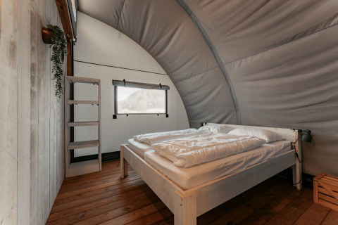 Knusse slaapkamer met groot bed en houten vloer bij Arcade, Camping de Italiaanse Meren, Nederland.