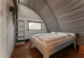 Knusse slaapkamer met groot bed en houten vloer bij Arcade, Camping de Italiaanse Meren, Nederland.