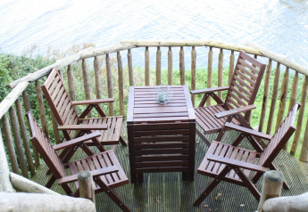 Houten terras met vier stoelen en tafel aan het water bij Ooievaarsnest, Camping de Koeksebelt, Nederland.