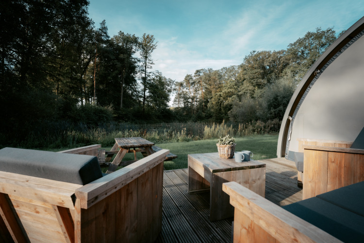 Terrasse mit Holzmöbeln an der Arcade-Lodge, umgeben von Wald, Camping de Italiaanse Meren, Niederlande.