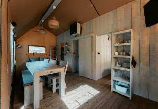 Interno della Ranger Lodge al Camping de Italiaanse Meren nei Paesi Bassi con arredi in legno chiaro.