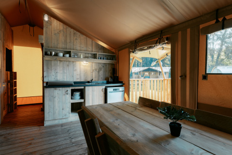 Interior de la tienda Safari Lodge XL con muebles de madera y cocina en Camping de Italiaanse Meren, Países Bajos.