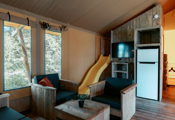 Interno del Safari Lodge XL al Camping de Italiaanse Meren con arredi in legno, scivolo e frigorifero.