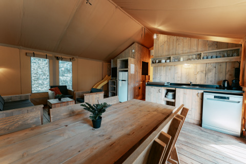 Indvendig udsigt af Safari Lodge XL teltet på Camping de Italiaanse Meren med køkken og spiseplads.