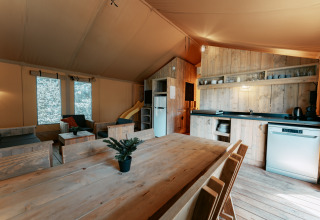 Indvendig udsigt af Safari Lodge XL teltet på Camping de Italiaanse Meren med køkken og spiseplads.