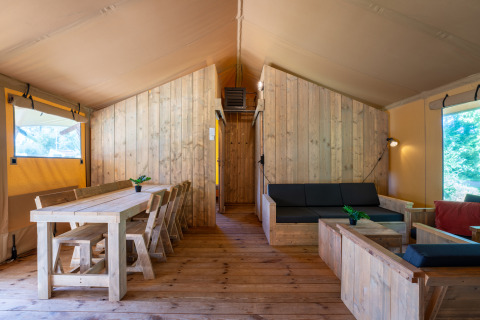 Innenraum des Safari Lodge XL Zeltes auf Camping de Italiaanse Meren in den Niederlanden mit Holzmöbeln.