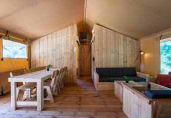 Indretning af Safari Lodge XL telt på Camping de Italiaanse Meren i Holland med træmøbler og sofa.