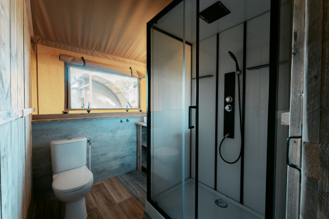 Baño moderno dentro de la tienda safari Nomad XL en Camping de Italiaanse Meren con ducha y sanitario.
