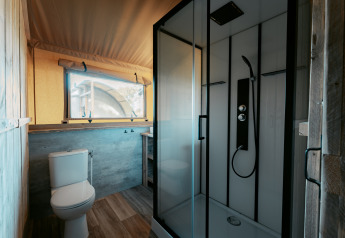 Baño moderno dentro de la tienda safari Nomad XL en Camping de Italiaanse Meren con ducha y sanitario.